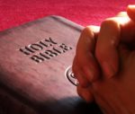 stock photo Clasped Hands on leather bound Holy Bible